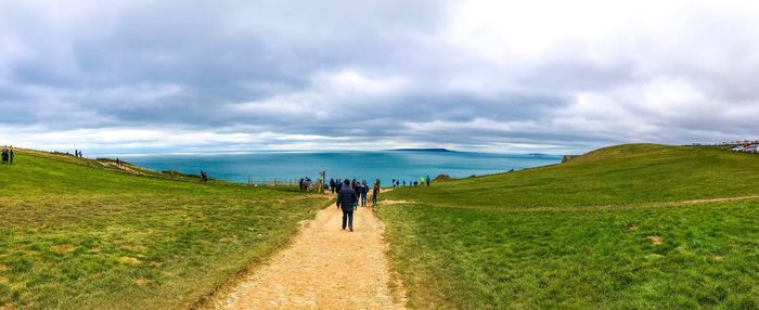 Rear view of people walking on land against sky