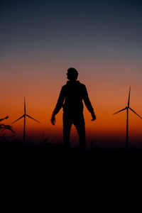 Silhouette woman standing on field against sky during sunset