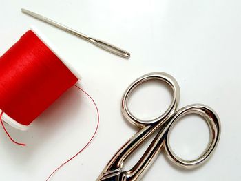 High angle view of thread spool and scissor on white background