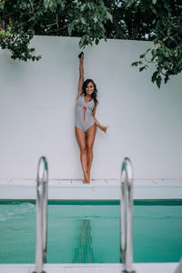 Full length of woman standing by swimming pool