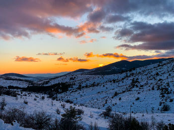 Scenic view of snow covered mountains against sky during sunset