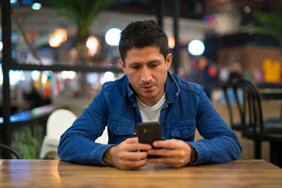 Mid adult man using mobile phone while sitting on table