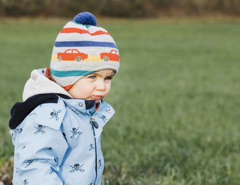 Cute girl wearing knit hat standing on field