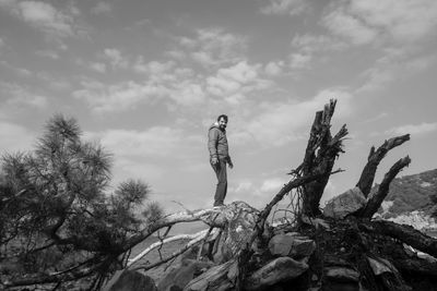 Low angle view of man standing on tree against sky