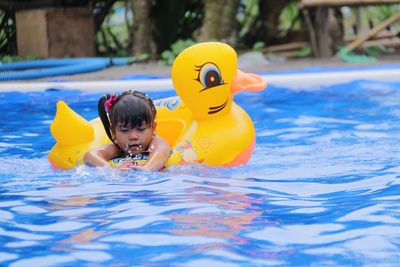 Girl with inflatable duck swimming in pool