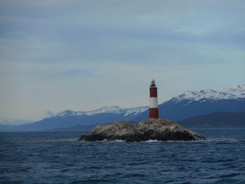 Lighthouse by sea against sky