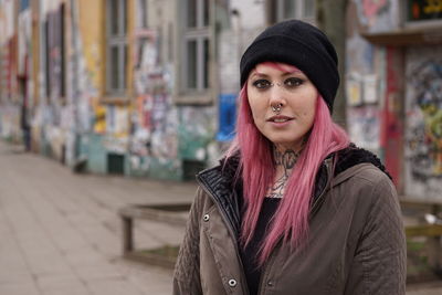 Portrait of young woman with pink hair standing on street