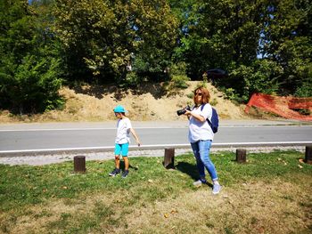 Mother photographing by son while standing on grassy field