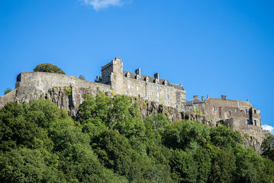 Low angle view of castle and trees against blue sky