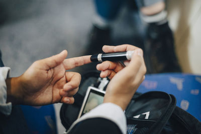 Cropped woman checking blood sugar level while sitting in train