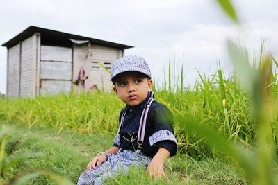 Cute boy looking away while sitting at farm