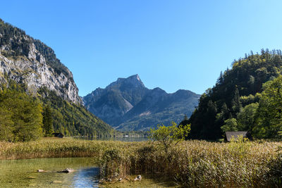 Scenic view of lake and mountains against clear blue sky