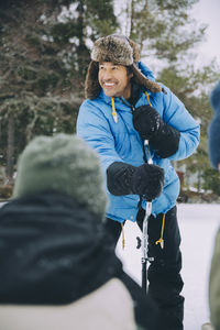 Happy mature man standing with ice auger during winter