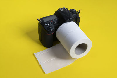 High angle view of camera with tissue paper on yellow background