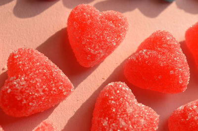 Sugar crystals coated red jelly heart candy close up on pink