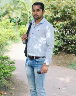 Portrait of young man standing against trees