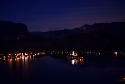 Scenic view of lake by silhouette mountain against sky at night