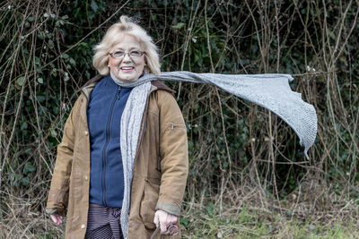 Portrait of smiling woman standing against trees