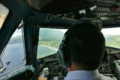 Rear view of pilot flying airplane over lake