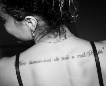 Close-up of text tattoo on woman back in darkroom