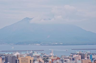 Aerial view of city by sea against sky