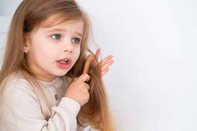 Cute girl combing hair against white background