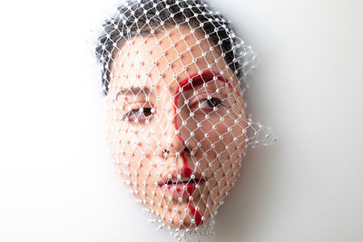 Close-up of thoughtful young woman with face covered by net taking milk bath