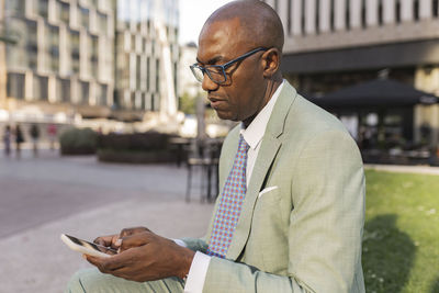 Mature businessman using mobile phone sitting at financial district