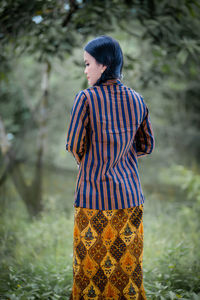 Rear view of young woman standing in forest