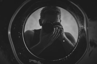 Man photographing with camera reflecting on mirror