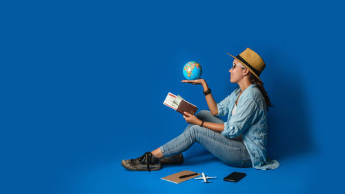 Digital composite image of woman holding umbrella against blue background