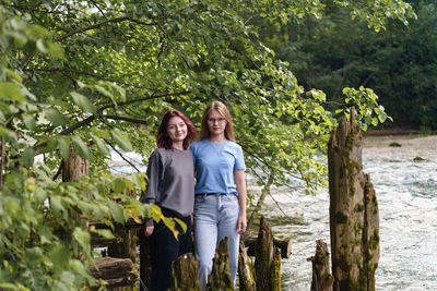 Portrait of smiling young woman standing against trees