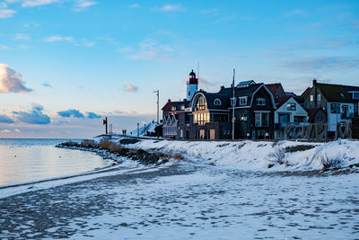 Houses and buildings against sky in city during winter