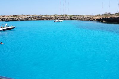 Sailboats moored in sea against blue sky