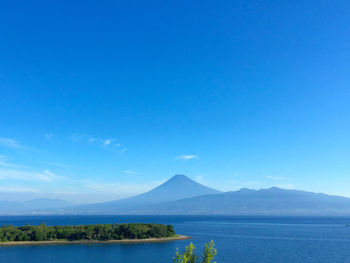 Scenic view of sea and mountains against clear blue sky