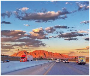 Cars on road against sky during sunset