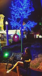 Woman sitting on illuminated bicycle at night