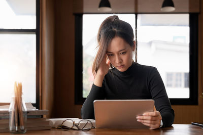 Young woman using laptop while sitting on table