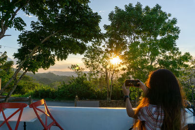 Rear view of woman photographing against sky