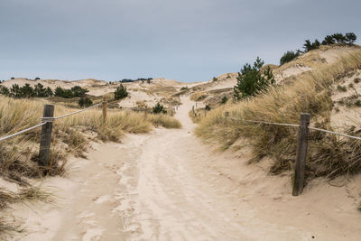 Road leading towards sand dunes against sky