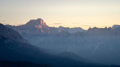 Rocky peak of mountain range catching the first light during sunrise, dolomites, italy