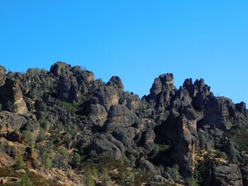 Low angle view of rocks against clear blue sky