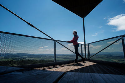 Silhouette of a girl on the observation deck with a panoramic view of the mountains and forest.