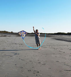 Full length of woman on beach against clear blue sky