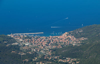 Aerial view of city by sea against blue sky