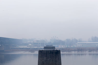 Buildings by lake against sky