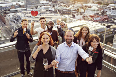 Portrait of cheerful business team with props and drinks enjoying after work party on terrace