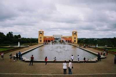 People by fountain against sky