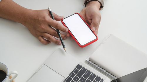 Cropped hand of man using mobile phone on table