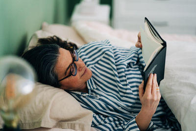 Midsection of woman lying down on bed at home